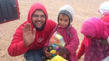 Juanfran Pastor con una de las niñas de Merzouga entregándole juguetes y material escolar durante el rally Maroc Challenge