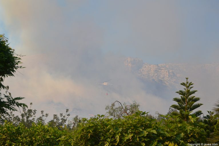 Helicóptero entre el denso humo que dificultaba las labores de extinción
