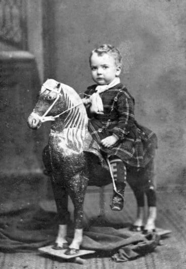 Niño subido al caballo de cartón