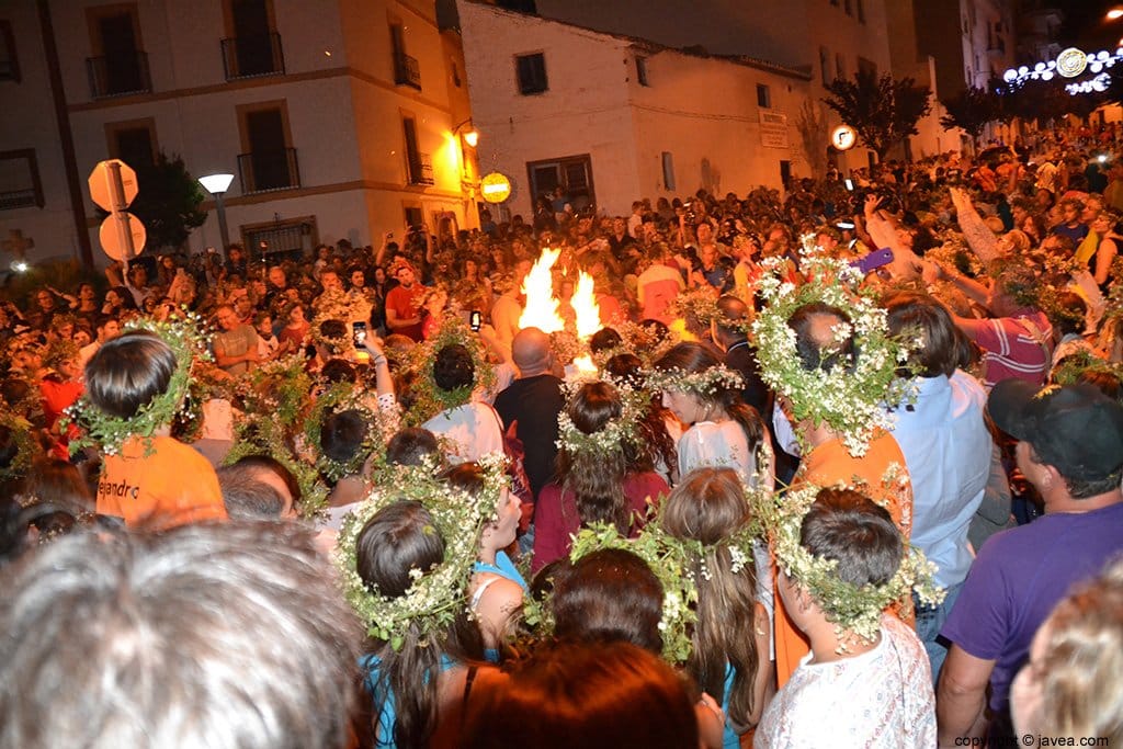 Multitud de gente participa saltando las fogueras