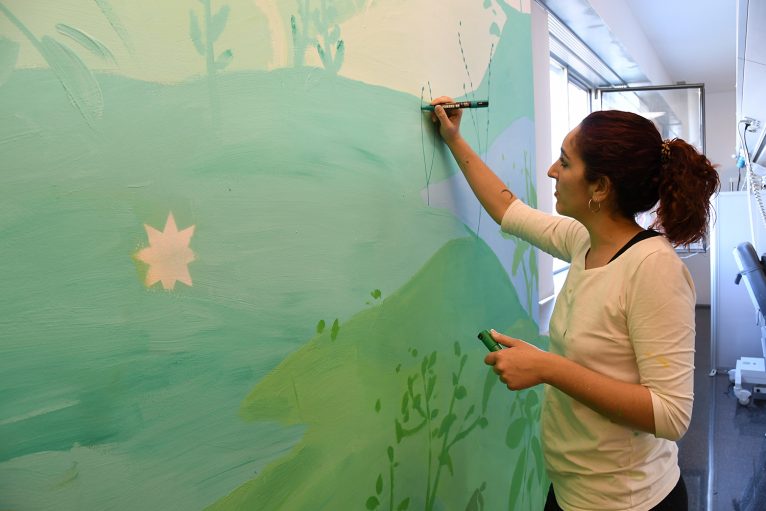 María Ortega pintando una de las paredes de la consulta del Hospital de Dénia