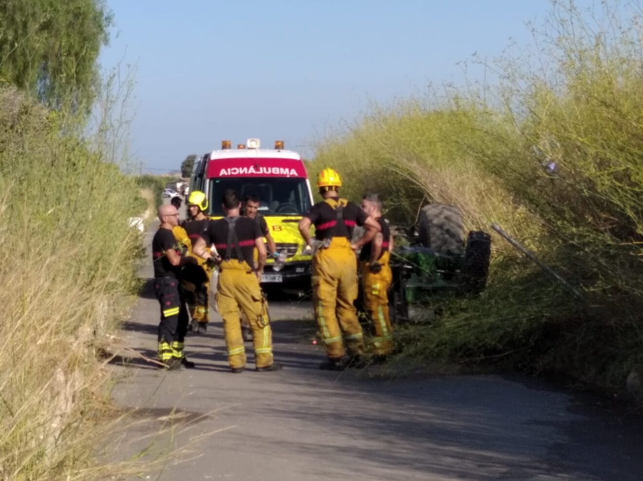 Bomberos y sanitarios junto al tractor volcado