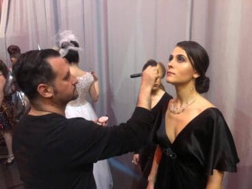 Óscar maquillando a una modelo en una pasarela de moda