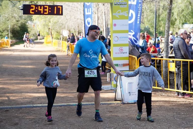 Un atleta con sus hijos cruzando la línea de meta