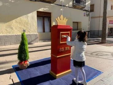 Una niña deposita la carta en el buzón real