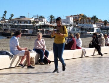 Mujer paseando con café en la playa del Arenal