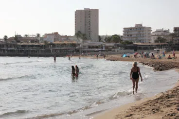 Los bañistas pasean por la orilla de la playa