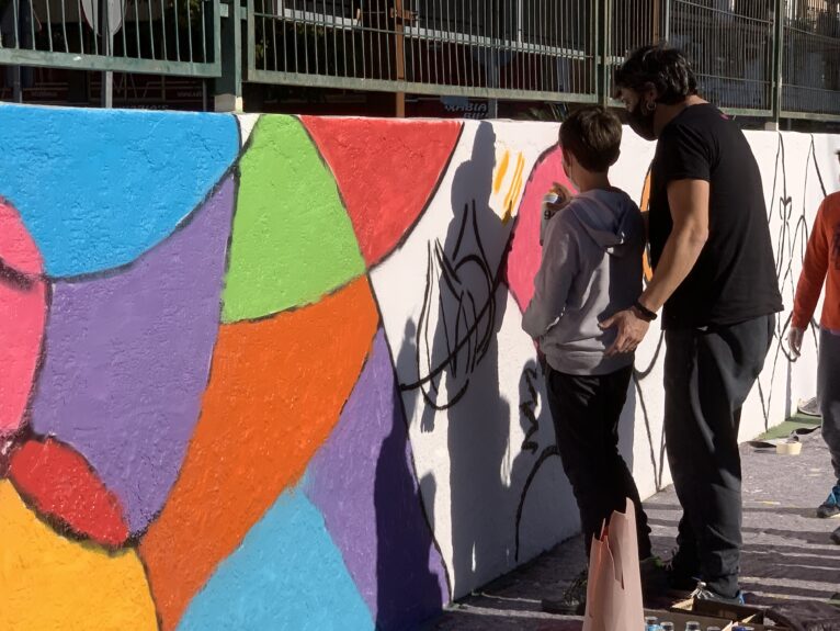 Un estudiante llena de color el mural del patio del CEIP Port de Xàbia