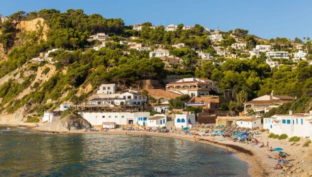 Imagen: Fachadas blancas tradicionales y zona de restauración a pie de playa en la cala