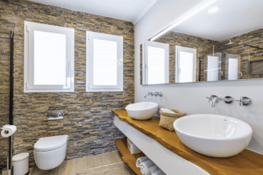 Baño con dos labavos y paredes de piedra