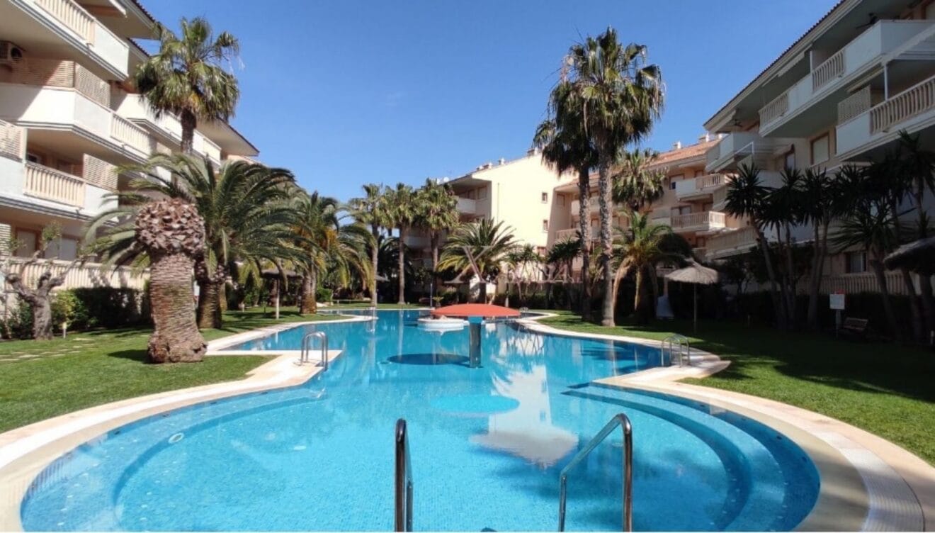 Apartamento con gran piscina comunitaria rodeada de césped