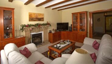 Salón estilo rústico equipado con dos sofás color crema junto a la chimenea