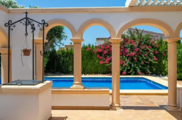 Terraza exterior con arcos que dan a la piscina y un pozo
