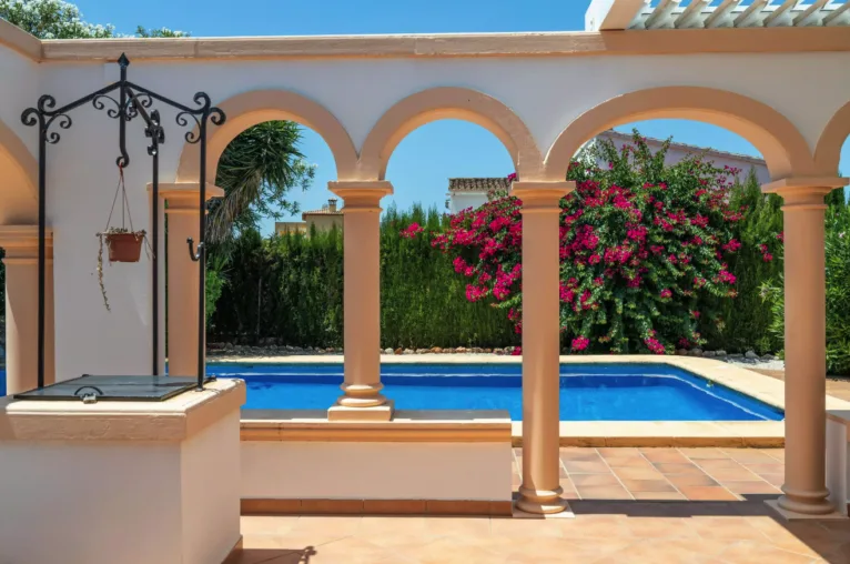 Terraza exterior con arcos que dan a la piscina y un pozo