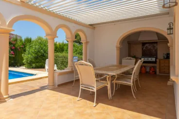 Zona de barbacoa exterior cubierta con comedor exterior y pérgola