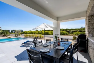 Zona de comedor exterior con barbacoa junto a la piscina