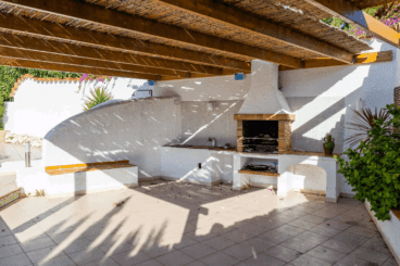 Zona de barbacoa a una altura inferior con pérgola