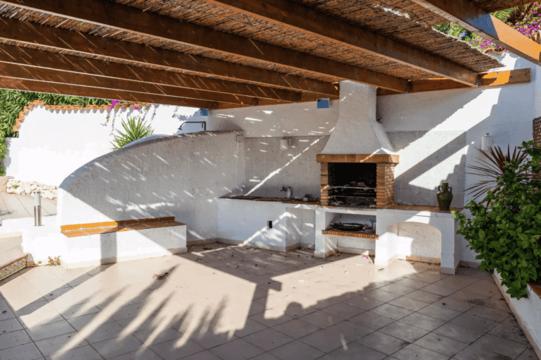 Zona de barbacoa a una altura inferior con pérgola
