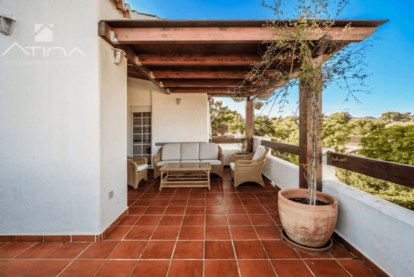 Terraza de la vivienda cubierta por una pérgola de madera