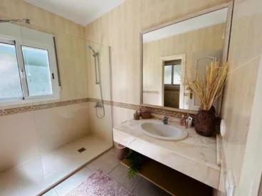 Baño de la vivienda con amplio plato de ducha y mampara