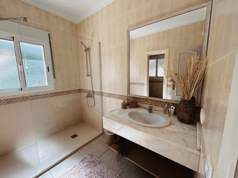 Baño de la vivienda con amplio plato de ducha y mampara