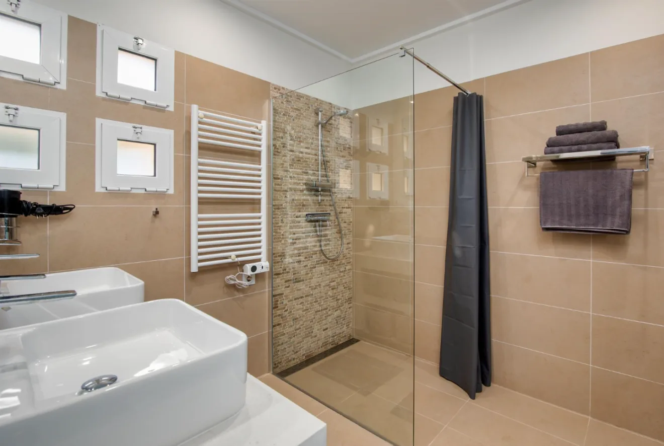 Moderno baño en suite con dos lavabos y plato de ducha con mampara de cristal