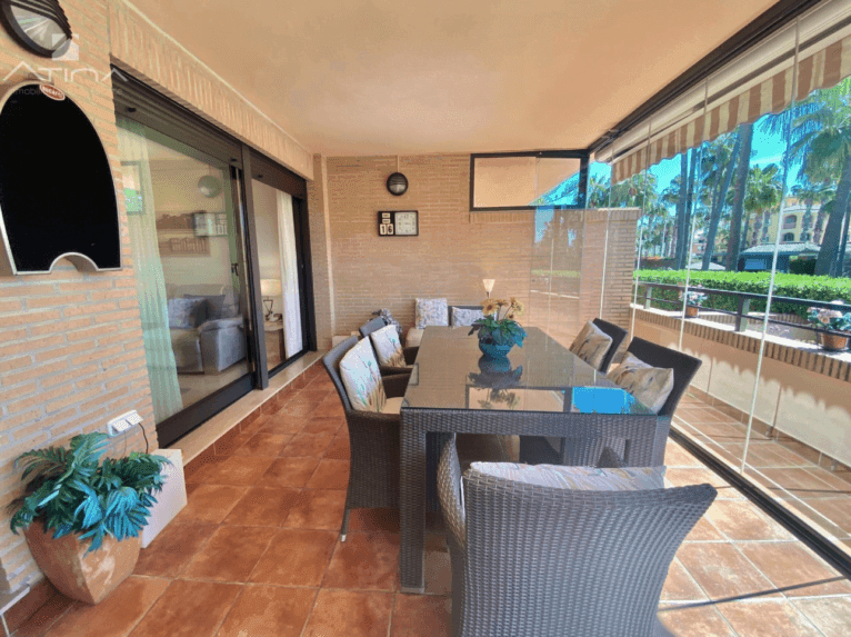 Terraza cubierta y acristalada de la vivienda con conjunto de comedor exterior