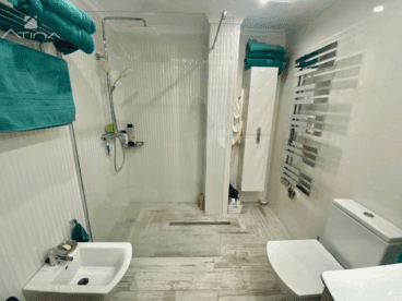 Un baño con un plato de ducha amplio y mampara de cristal