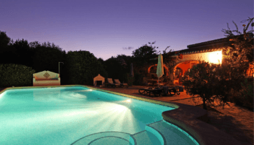 Piscina privada iluminada de noche en una villa de ensueño