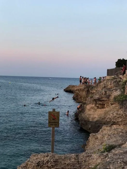 Imagen: Jóvenes saltando desde la Punta del Arenal de Xàbia ante el cartel de prohibido. Foto Enrique Ocaña -Xàbia Meravellosa