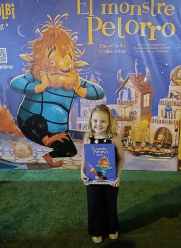 Photocall de El Monstre Petorro. Una niña posa con el cuento firmado