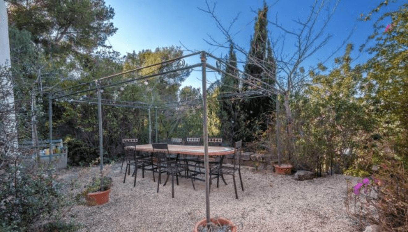 Zona de paellero bajo la pérgola, ideal para organizar comidas al aire libre en un ambiente acogedor