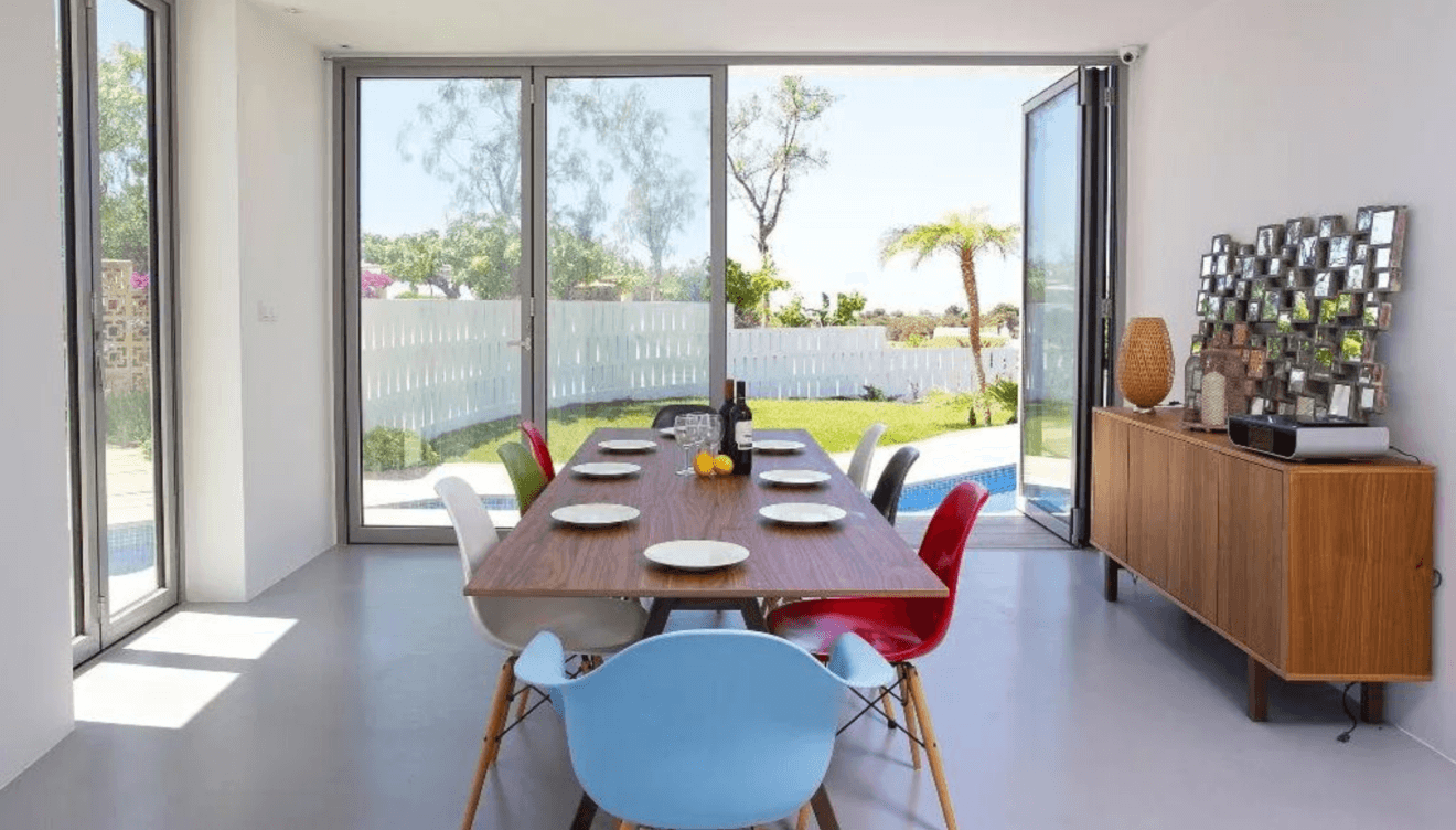 El comedor de la villa, conectado con el salón, se caracteriza por sus grandes ventanales que permiten que la luz natural inunde el espacio