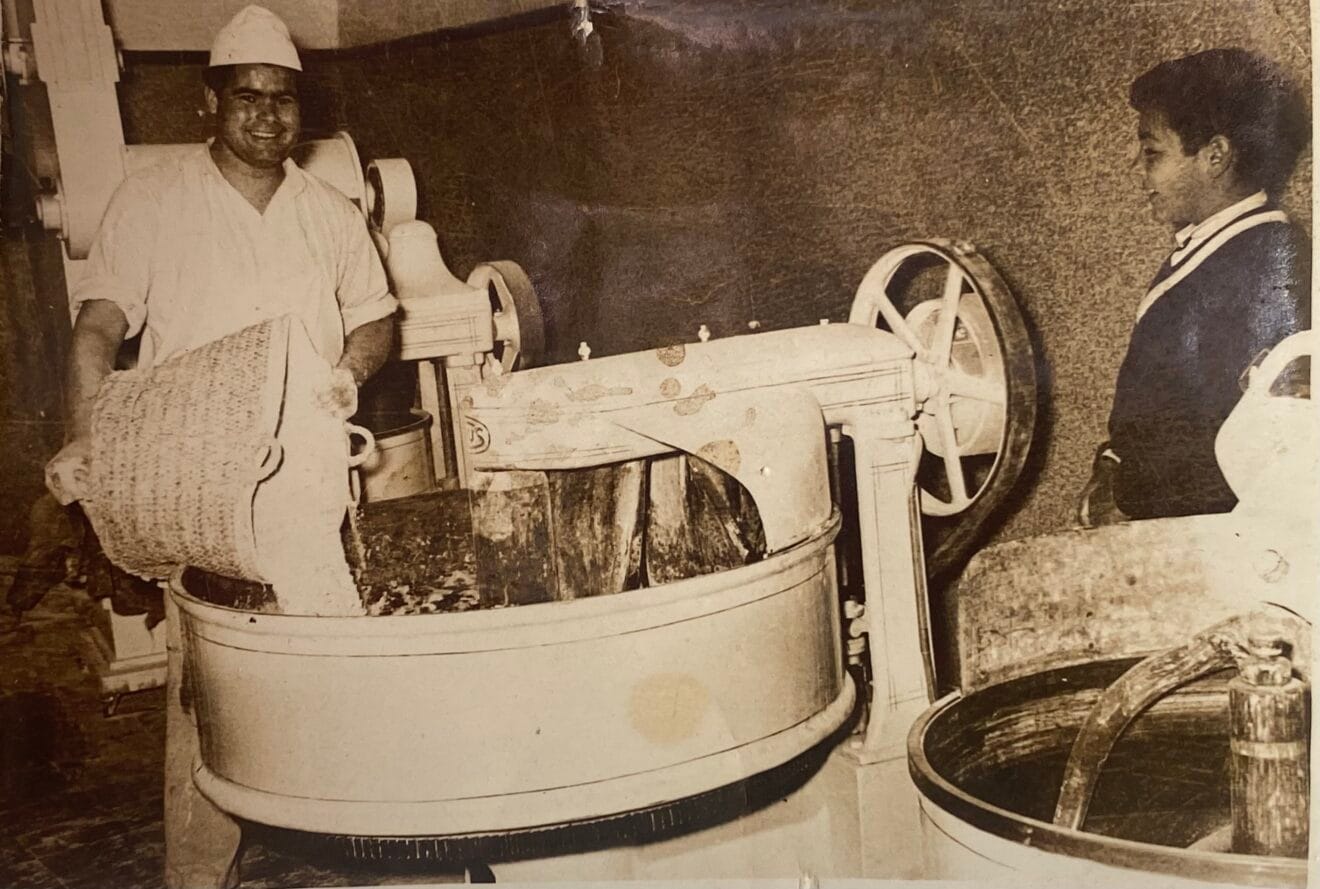 Antonio Bisquert Buigues -nieto- contempla la maquinaria de la Panificadora mientras un empleado vierte la harina. Año 1958. Foto Antonio Bisquert Buigues