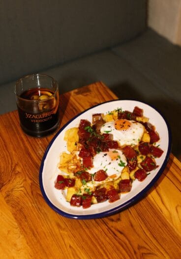 Huevos rotos con atún rojo y patatas fritas acompañado de un vermut