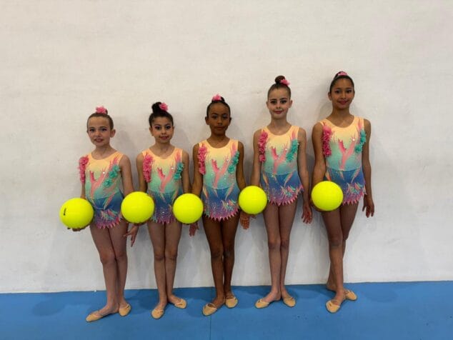 Imagen: Cinco gimnastas del Club Xàbia con maillots coloridos y pelotas amarillas posando juntas.
