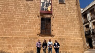 El equipo organizador exhibe los folletos de las fiestas del Nazareno ante la fachada de la iglesia