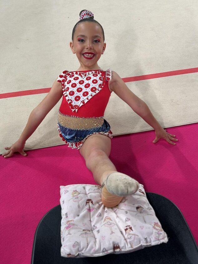 Imagen: Fotografía de la joven gimnasta Iris posando sonriente en el tapiz, en el contexto del Campeonato Nacional en Oviedo.