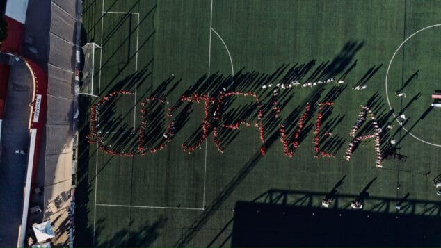 Imagen: Vista aérea de personas formando las letras 'CD JAVEA' en un campo de fútbol.