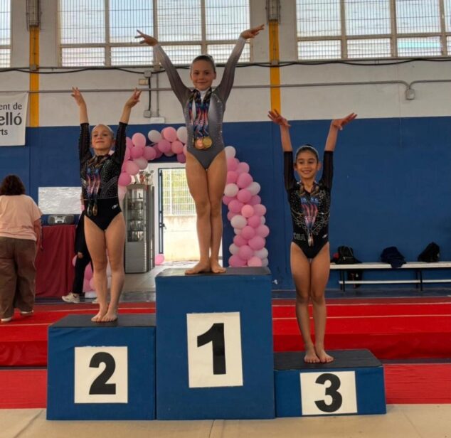 Tres gimnastas del CD Montgó con medallas en el podio del campeonato provincial de Castellón, levantando los brazos.