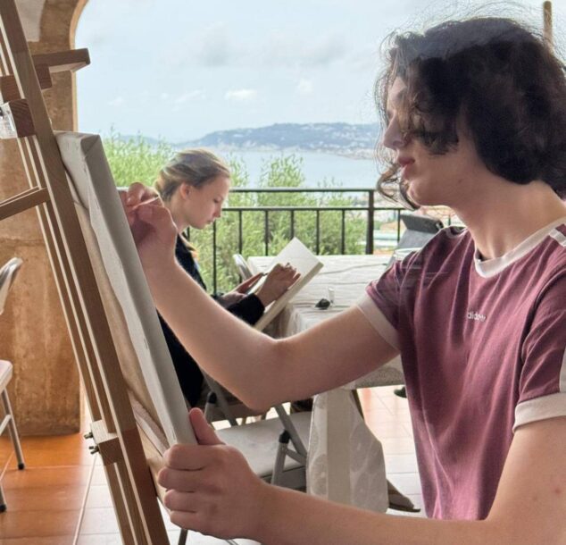 Dos jóvenes artistas pintando al óleo en caballetes en una terraza con vistas al mar en Jávea, durante su residencia artística.