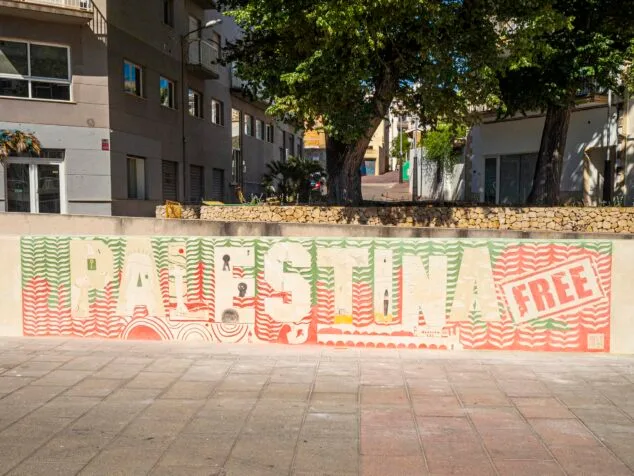 Imagen: Mural de esgrafiado en una pared de piedra con el texto "PALESTINA FREE" y elementos simbólicos palestinos en tonos rojos y verdes.