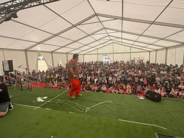 Paco Cholbi en el escenario presentando el espectáculo del Monstruo Petorro ante una carpa llena de público.
