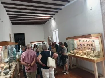 Grupo de visitantes observando vitrinas con piezas arqueológicas durante una visita guiada en el interior del Museu Soler Blasco.