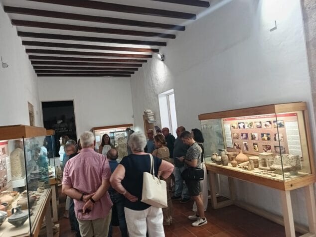 Grupo de visitantes observando vitrinas con piezas arqueológicas durante una visita guiada en el interior del Museu Soler Blasco.