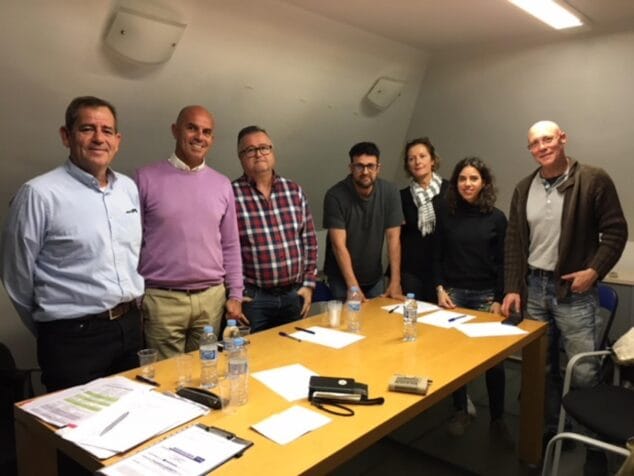 Fotografía de grupo de varios miembros de la Junta Directiva de la Asociación de Empresarios del Arenal de Xàbia posando alrededor de una mesa de reuniones.