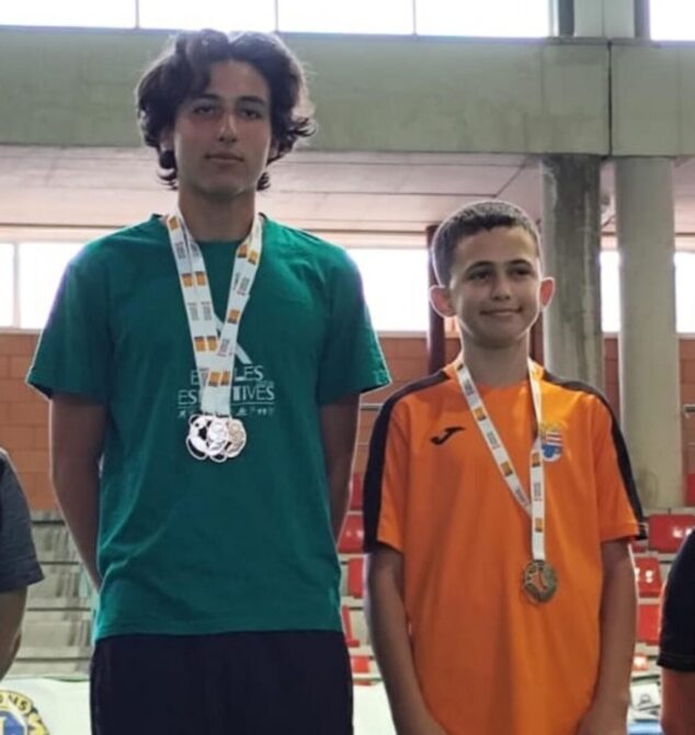 Imagen: Pau Ibañez y Josep Ivars, jóvenes jugadores de bádminton, de pie en el primer puesto del podio mostrando sus medallas.