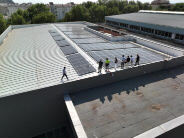 Varias personas, incluida la alcaldesa Rosa Cardona, observan las placas solares en la cubierta de la piscina municipal de Xàbia.