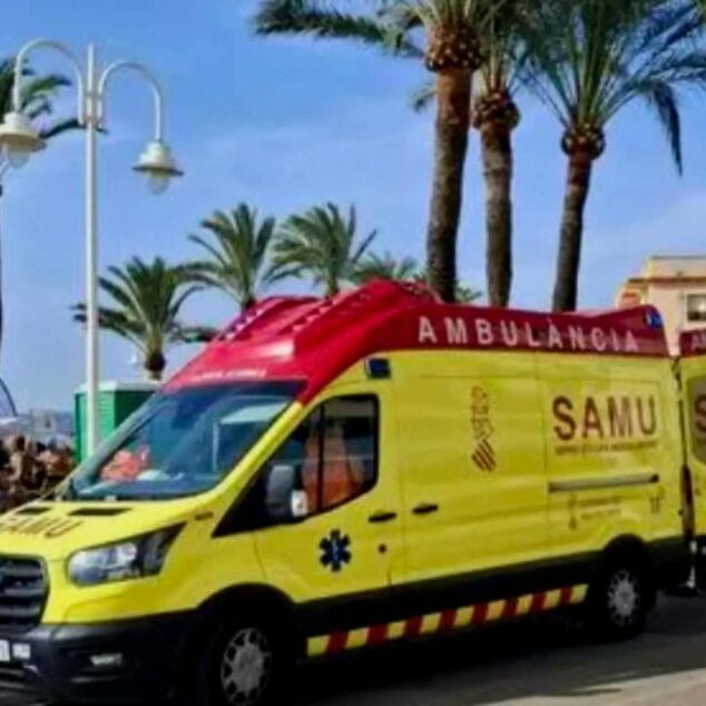 Imagen: Ambulancia del SAMU amarilla y roja aparcada cerca de una zona de playa con palmeras al fondo.