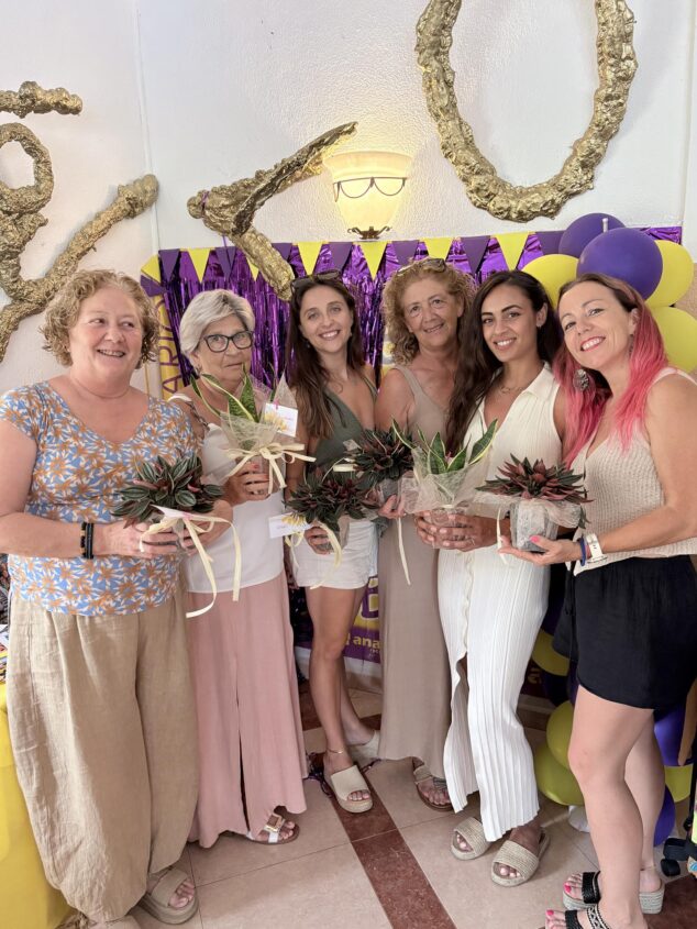 Imagen: Seis mujeres posan juntas sosteniendo plantas durante la celebración del 20 aniversario del Club Gimnàstica Rítmica Xàbia.
